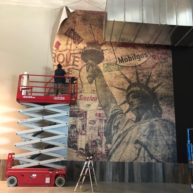 Person on lift installing Statue of Liberty mural
